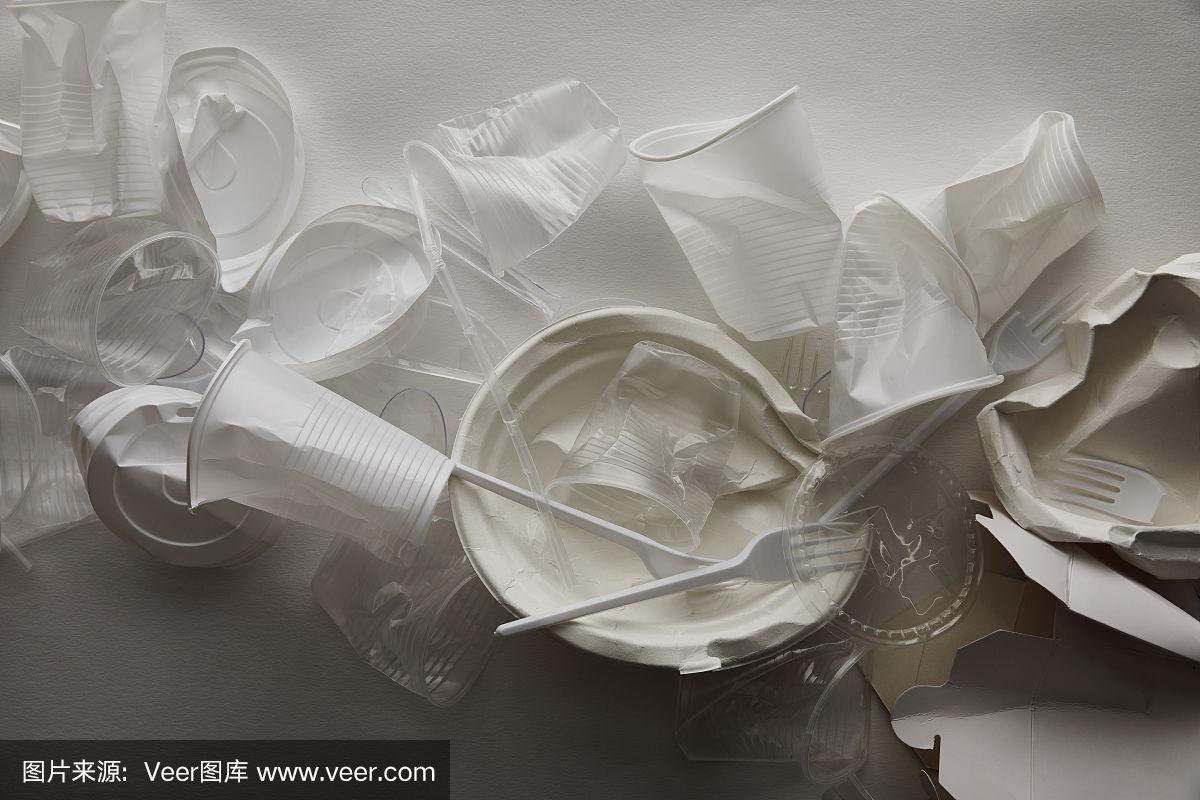 俯视图皱巴巴的塑料杯,盘子和纸板容器在白色的背景与阴影
